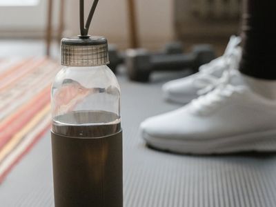Modern reusable water bottle next to a workout mat.